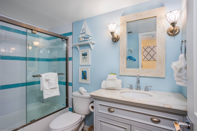 Refresh in your coastal-themed bathroom with glass shower, marble vanity, and charming nautical touches that create a serene seaside escape.