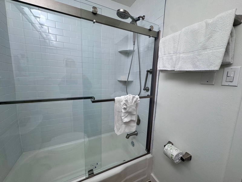 Step into your modern bathroom where fresh towels await and a spacious shower beckons for a refreshing start to your day.