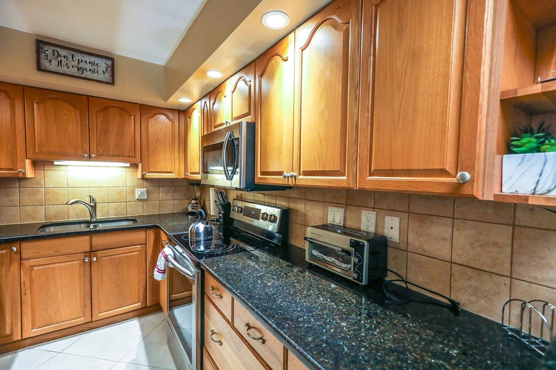 Your fully equipped kitchen offers warm wood cabinetry, granite countertops, and modern appliances for creating delicious home-cooked meals during your stay.