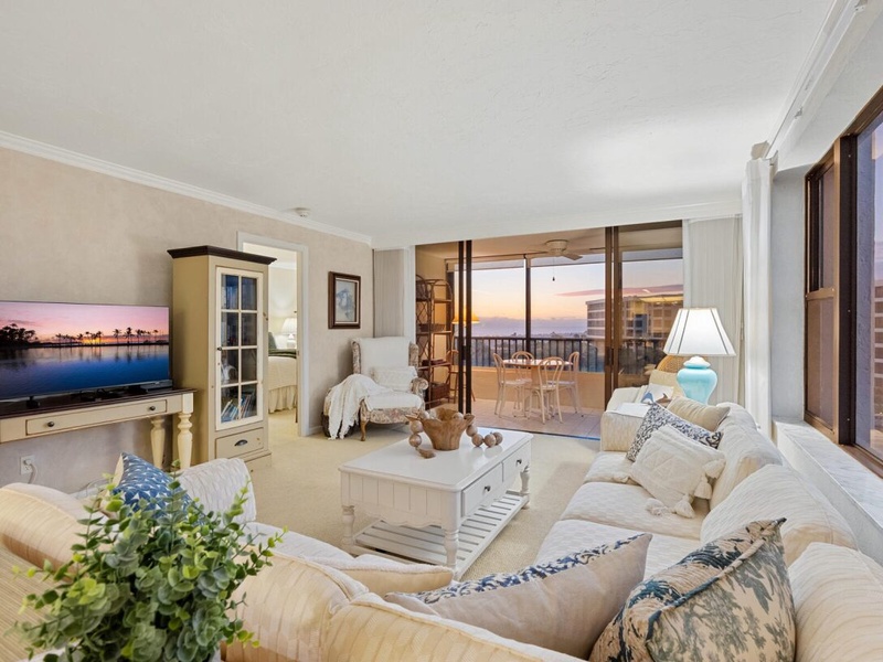 Relax in your beautifully furnished living room with coastal charm, featuring plush seating and stunning ocean views from your private balcony.