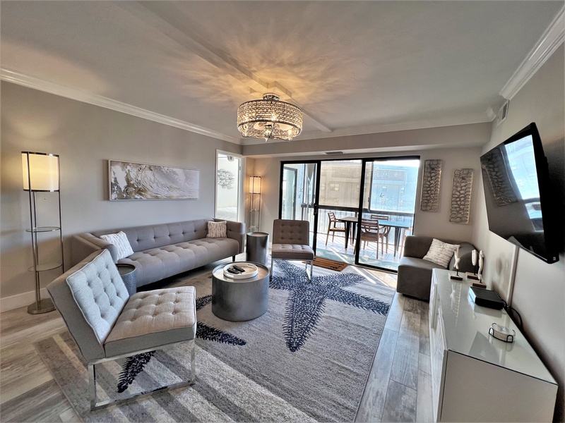 Sink into modern luxury with plush seating, stunning chandelier, and your private balcony overlooking the city.