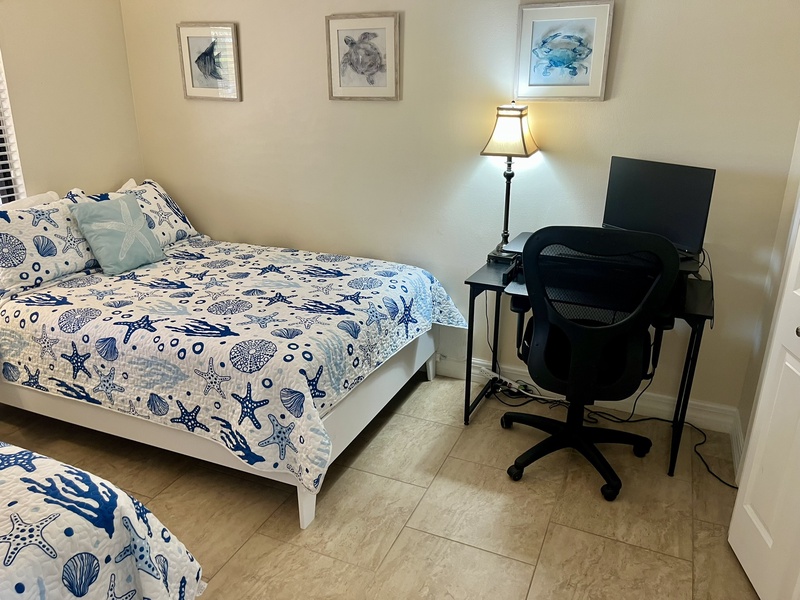 Your coastal-themed bedroom features comfortable beds and a dedicated workspace, perfect for both relaxation and productivity during your stay.