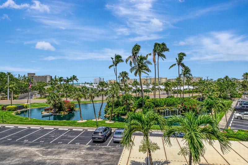Tropical paradise view overlooking lagoon pools, swaying palms, and coastal cityscape under endless blue skies.