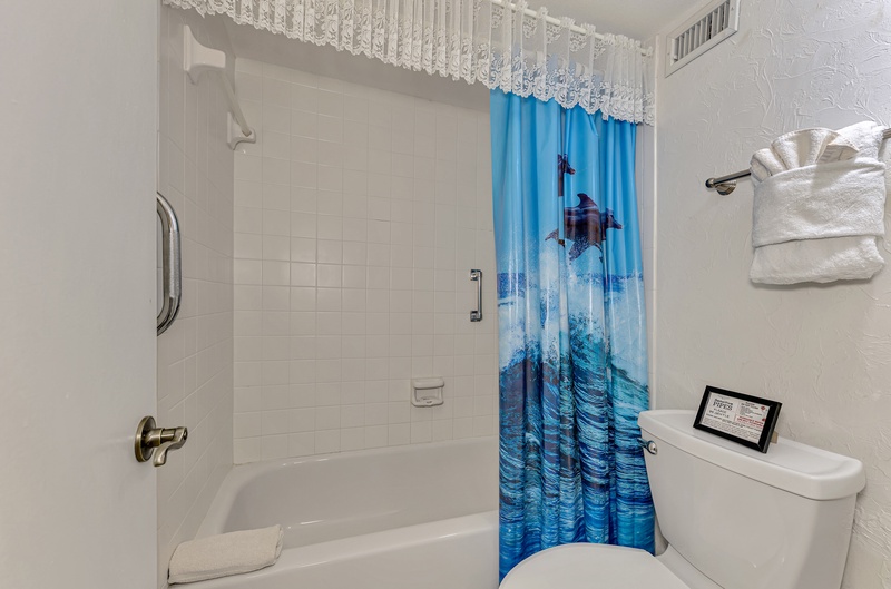 Refresh in your private bathroom featuring a full tub-shower combo and whimsical ocean-themed curtains that bring coastal charm to your daily routine.