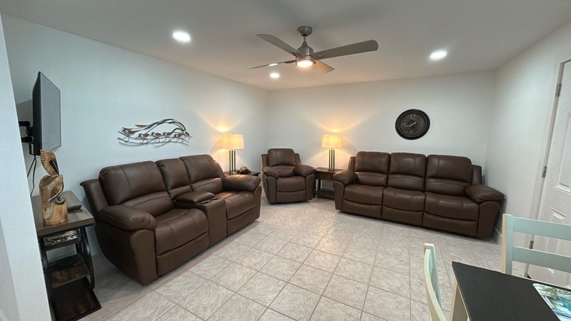 Sink into luxurious leather recliners in your spacious living area, where warm lighting and a ceiling fan create the perfect atmosphere for movie nights.