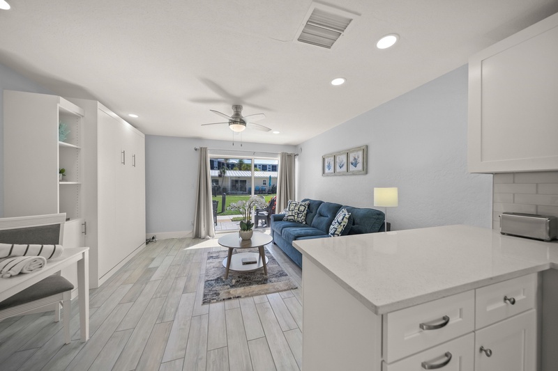 Your stylish open-concept living space flows seamlessly from kitchen to lounge, featuring modern finishes and a cozy blue sofa perfect for relaxation.