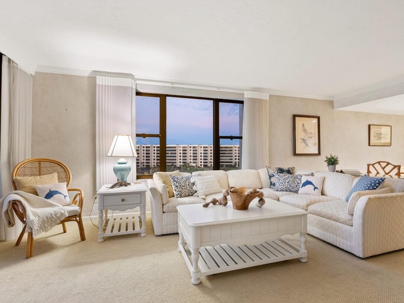 Sink into plush sofas while enjoying stunning city views through floor-to-ceiling windows in this elegantly furnished living space.