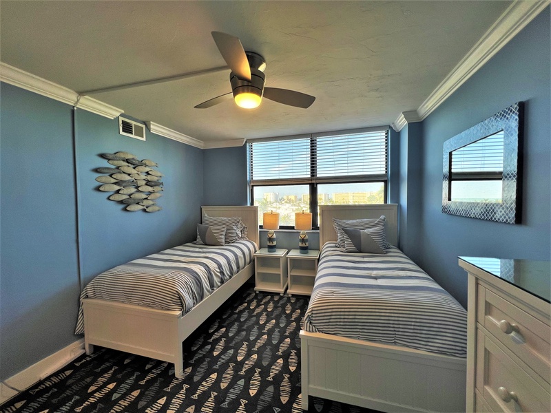 Drift off to sleep in your coastal twin bedroom with calming blue walls, striped linens, and gentle ceiling fan breeze.