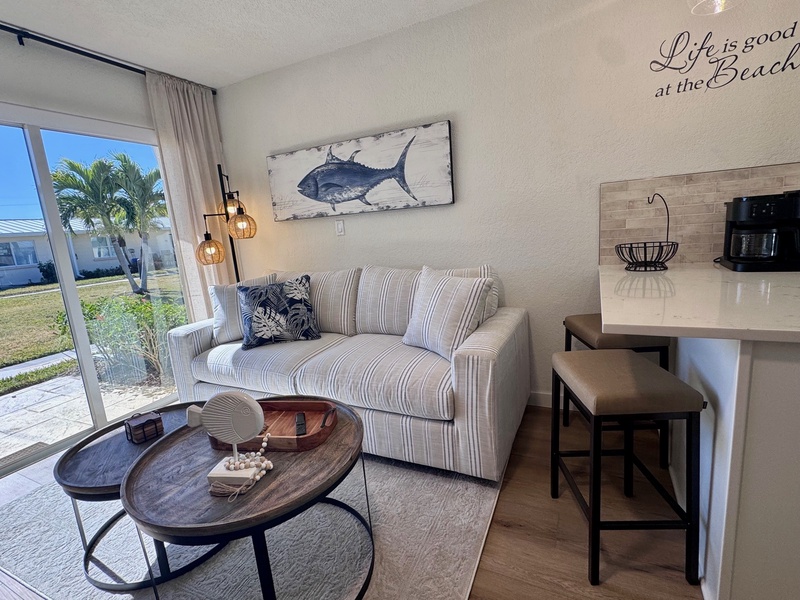 Your coastal-themed living room blends comfort with beach vibes—relax on the striped sofa while tropical palm trees sway outside your window.