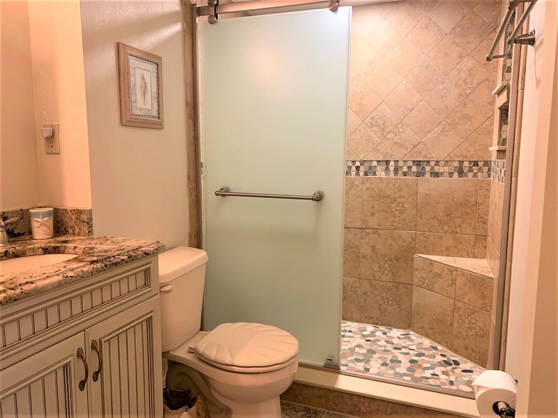 Step into your private bathroom featuring elegant tile work, granite countertops, and a spacious walk-in shower with custom mosaic flooring.