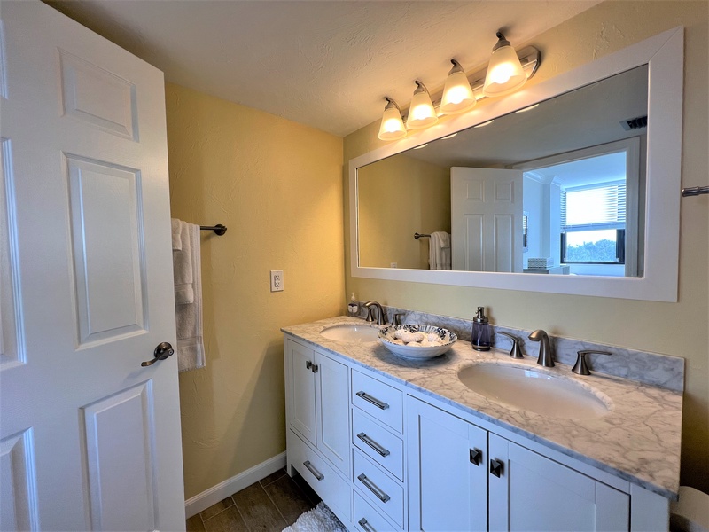 Freshen up in your stylish bathroom with dual sinks, elegant marble counters, and warm lighting for your morning routine.