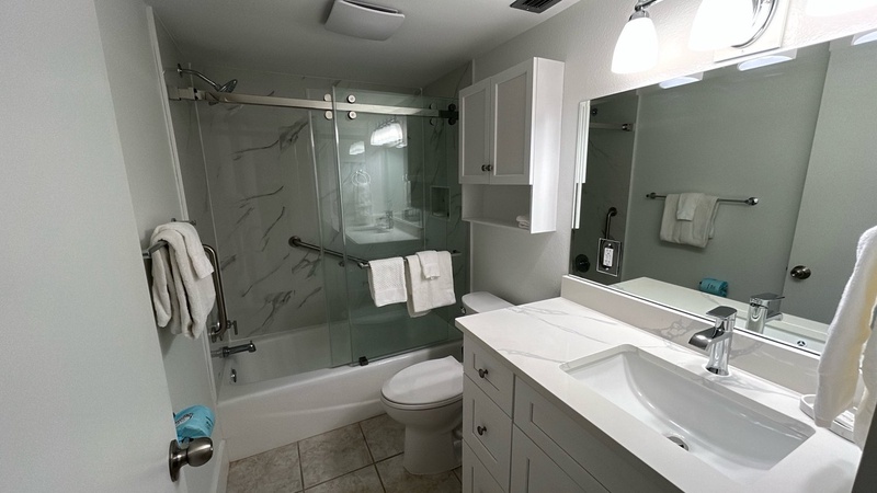Step into your modern bathroom featuring a sleek glass shower, marble-style walls, and pristine white vanity with premium fixtures.