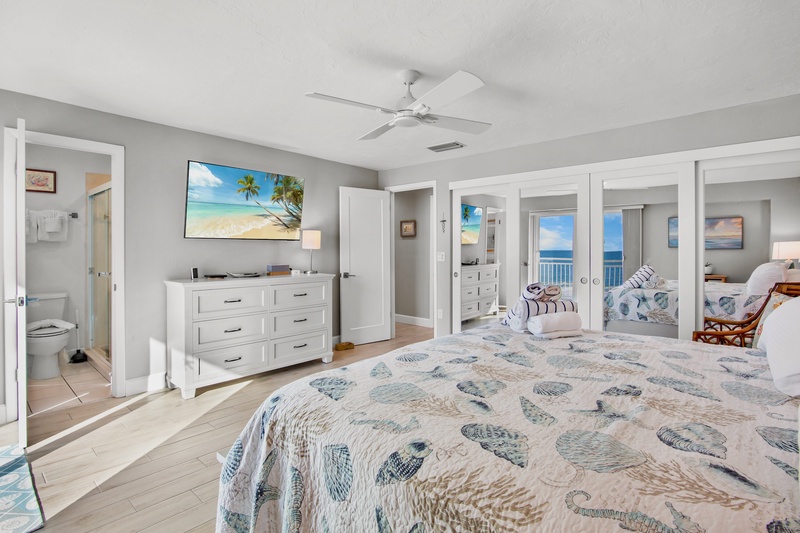 Wake up to ocean views through your private balcony doors in this coastal master suite with tropical touches and modern comfort.
