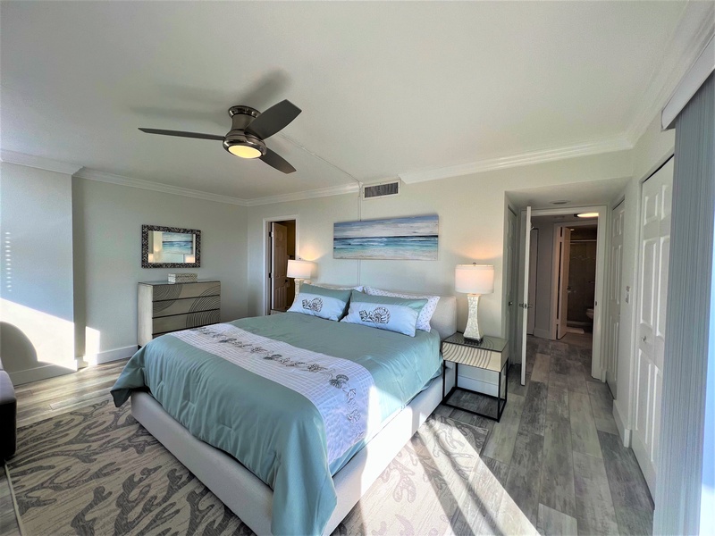 Your peaceful bedroom retreat awaits with ocean-inspired décor, cooling ceiling fan, and serene coastal artwork creating the perfect sleep sanctuary.