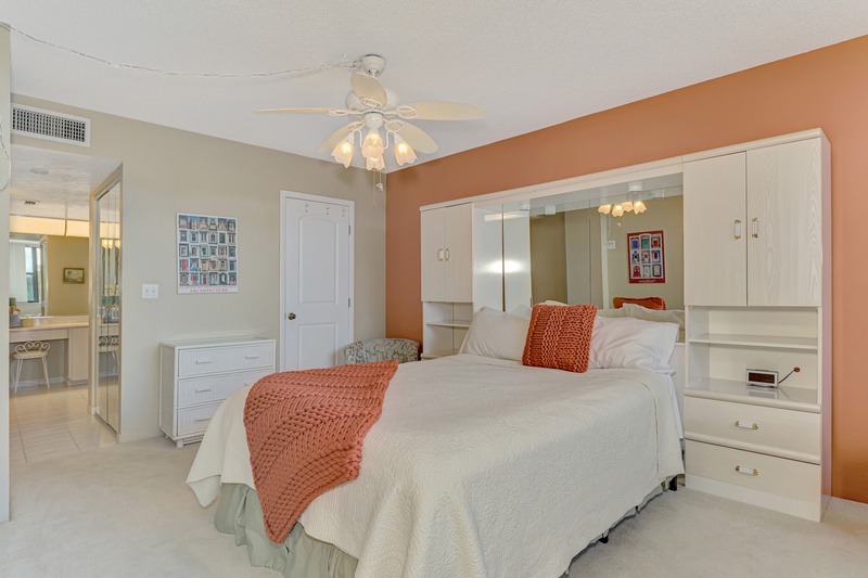 Sink into your spacious bedroom with built-in storage, vibrant coral accents, and peaceful ambiance for restful nights.