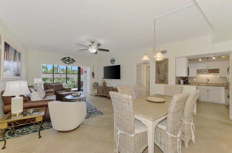 Your open-concept living space seamlessly blends comfort and coastal style, with wicker dining chairs and leather sofas perfect for relaxing.