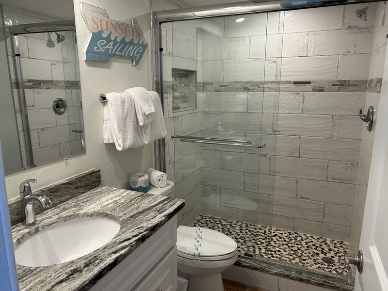 Unwind in your beautifully renovated bathroom featuring a spacious walk-in shower with elegant glass doors and plush towels awaiting your arrival.