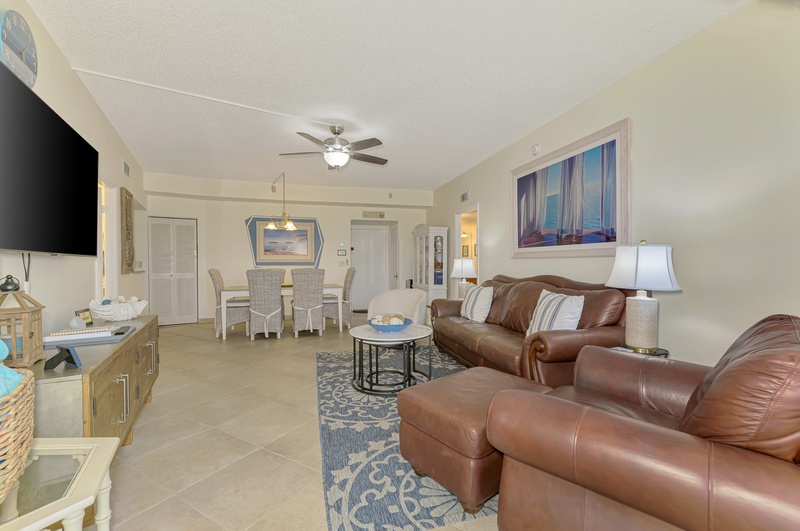 Relax in your spacious living room with plush leather seating, coastal décor, and open layout connecting to your dining area.
