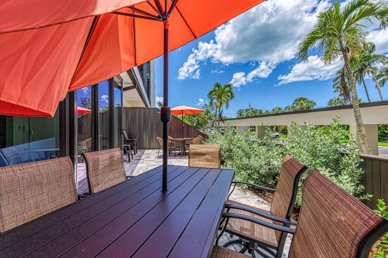 Unwind on your private deck with tropical garden views and comfortable wicker seating under bright orange umbrellas.
