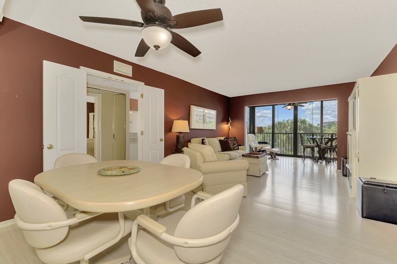 Relax in your spacious living area featuring comfortable seating, dining space, and stunning balcony views of lush greenery beyond.