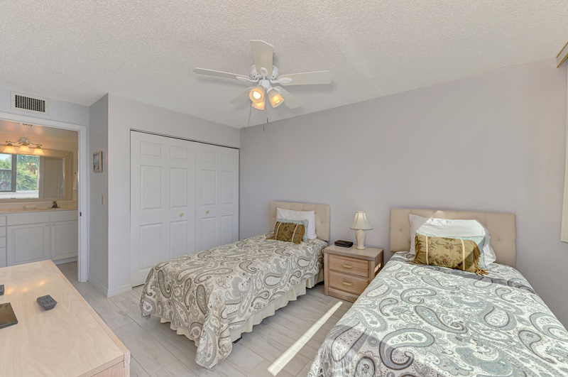 Your comfortable twin bedroom offers two cozy beds with paisley linens, ceiling fan, and convenient bathroom access for peaceful rest.