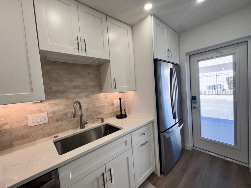 Your modern kitchen features crisp white cabinetry, stainless steel appliances, and elegant marble countertops with subway tile backsplash.