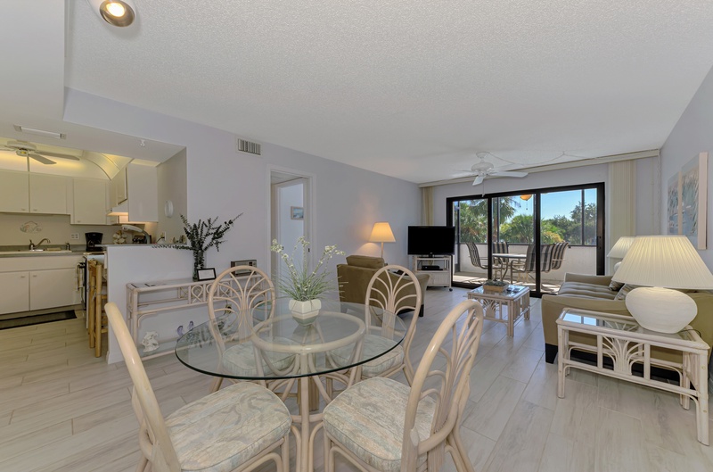 Your bright, airy condo features an open layout connecting kitchen, dining, and living areas with tropical views through sliding doors.