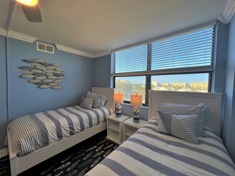 Wake up to stunning city views in this stylish twin bedroom with coastal-inspired decor and comfortable furnishings for your perfect getaway.