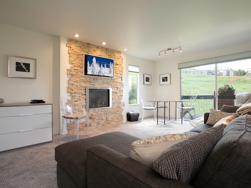 Unwind in your spacious living room featuring a cozy stone fireplace, large windows framing the golf course, and plush seating perfect for relaxing evenings.