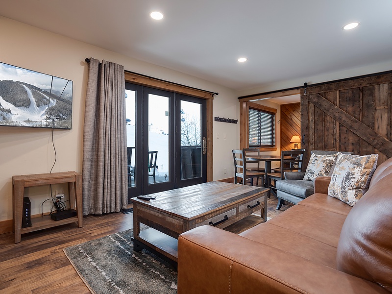 Relax in your inviting living space with rich leather seating, rustic wood accents, and mountain views streaming through the glass doors to your private patio.