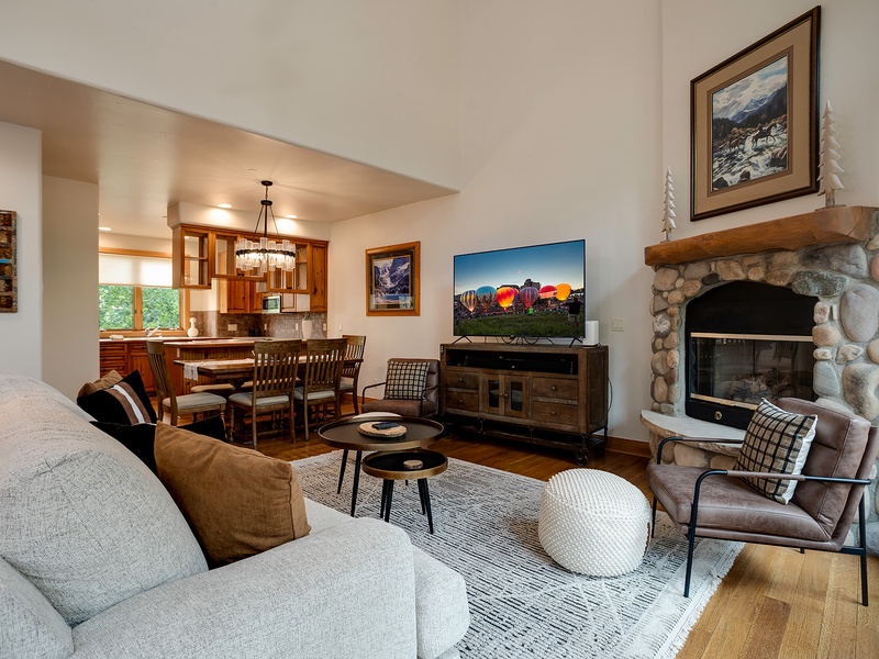 Settle into your cozy living room with a stone fireplace, plush seating, and an open flow to the dining area and kitchen—perfect for relaxing after mountain adventures.