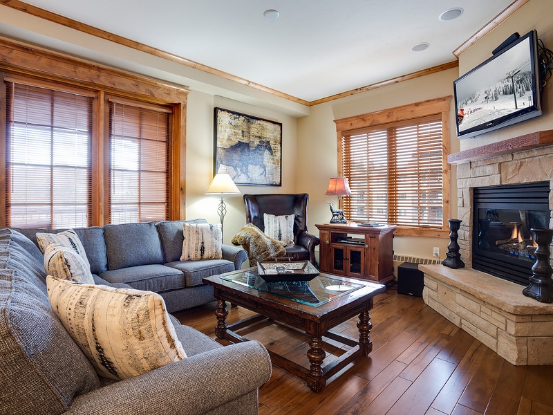 Sink into plush seating by your glowing fireplace, surrounded by warm wood accents and mountain charm—your cozy retreat after a day of adventure.
