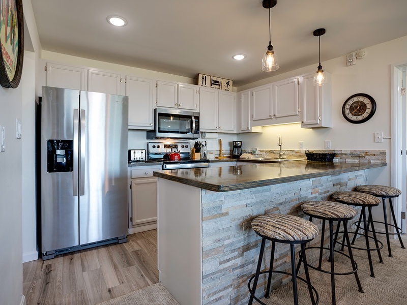Your modern kitchen awaits with gleaming appliances, ample counter space, and a breakfast bar perfect for your morning coffee or casual meals together.