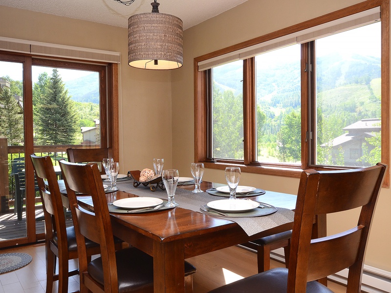 Gather around your dining table where mountain vistas frame every meal. Natural light fills this welcoming space, inviting you to linger over breakfast as the morning sun illuminates the peaks beyond.