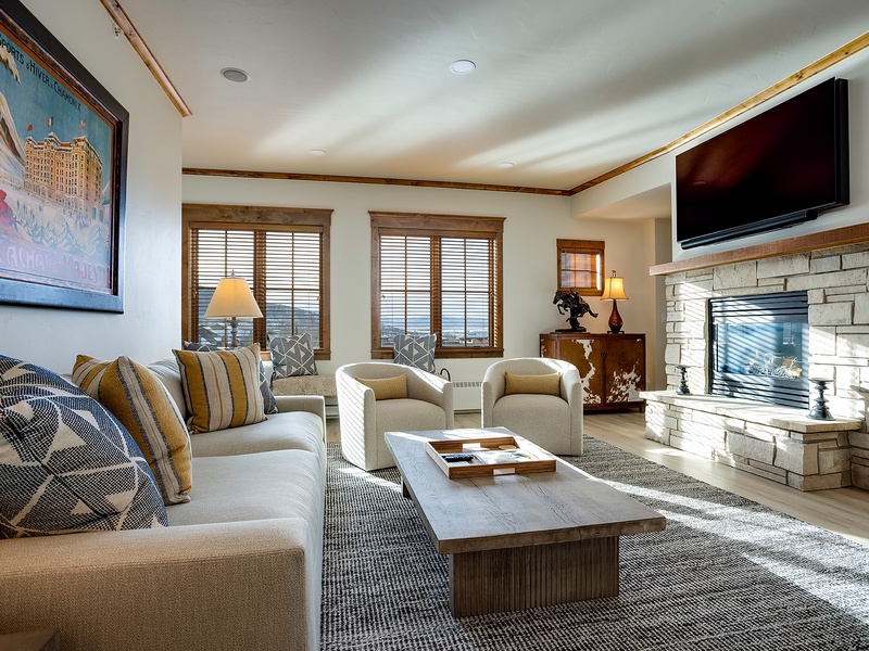 Sink into plush seating by the fireplace, where mountain views frame your mornings and entertainment awaits on the flat-screen TV—your perfect retreat for relaxing together.