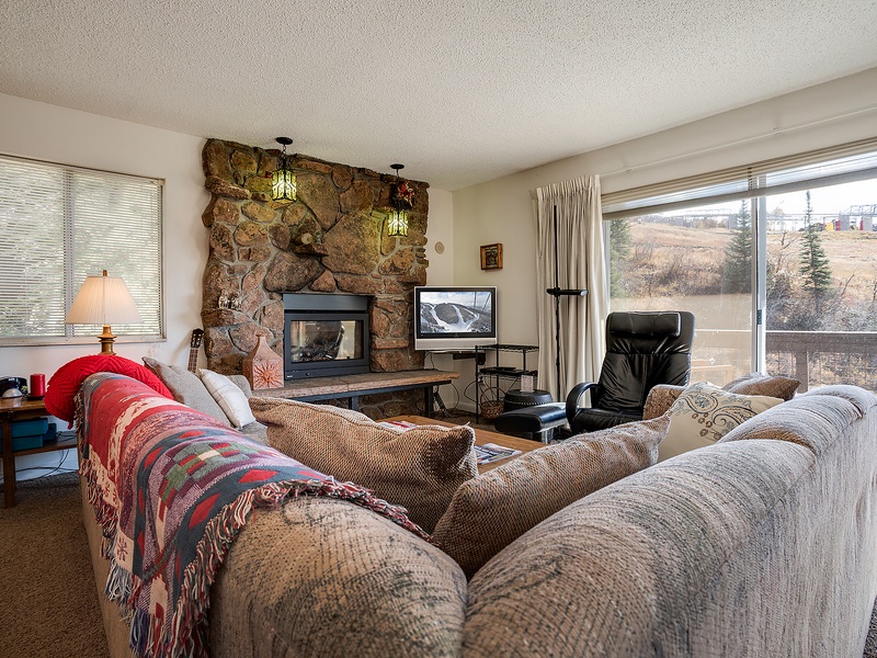 Curl up on plush sofas by the stone fireplace while enjoying your private balcony views of the natural landscape beyond your mountain retreat.
