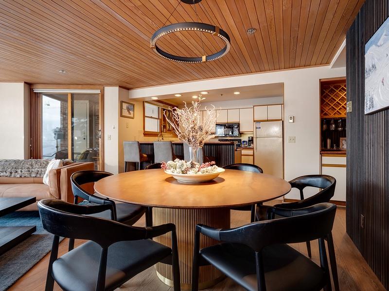 Gather around this stunning table beneath warm wood ceilings—your elegant dining space flows seamlessly into a fully-equipped kitchen, perfect for sharing meals and memories.