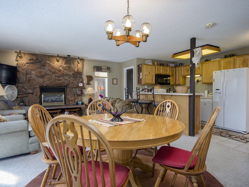 Gather around the dining table with rustic charm framing your mountain retreat. The stone fireplace and open layout create a cozy, inviting space perfect for your group getaways.