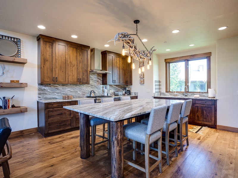 Gather around the spacious marble island where rustic elegance meets modern comfort. Rich wood cabinetry, gleaming countertops, and charming antler-inspired lighting create your perfect mountain retreat kitchen.