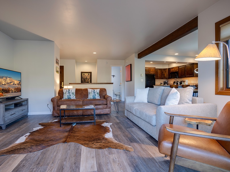 Relax in your open-concept living space featuring vaulted ceilings with rustic beams, plush seating for everyone, and a fully equipped kitchen ready for your culinary adventures.