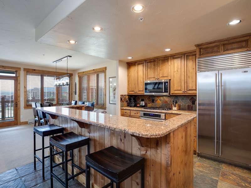 Your fully-equipped chef's kitchen features granite counters, stainless appliances, and a breakfast bar overlooking mountain views—perfect for morning coffee or group gatherings.