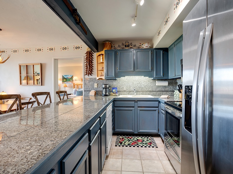 Your fully equipped kitchen features stainless steel appliances, granite countertops, and charming blue cabinetry—perfect for preparing meals at home during your stay.