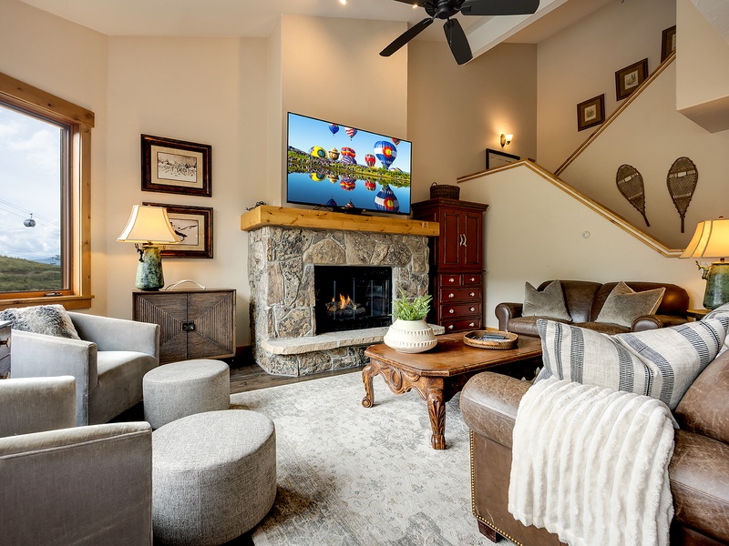 Sink into plush seating beside a crackling stone fireplace, where vaulted ceilings and mountain views through picture windows create your perfect retreat after a day of adventure.