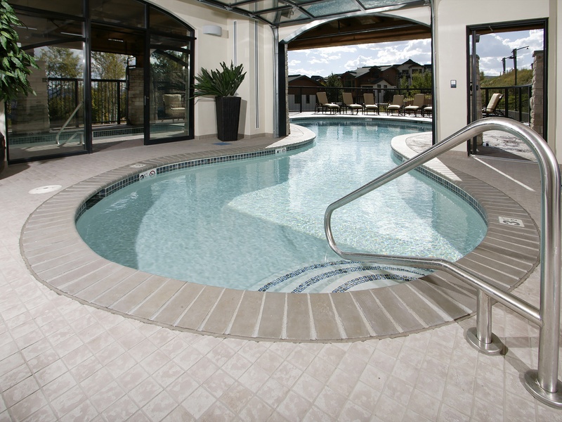 This inviting indoor-outdoor pool features a seamless flow connecting interior and exterior spaces, complete with spacious lounging areas and serene mountain views in the surrounding landscape.