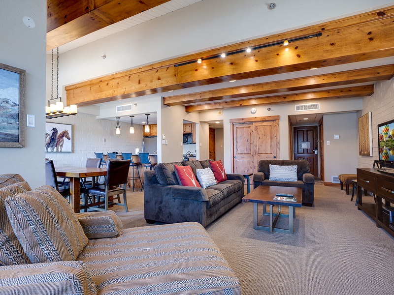 Unwind in your spacious open-concept living area, featuring soaring vaulted ceilings with rustic beams, plush seating, and mountain-inspired artwork that sets the tone for your alpine escape.