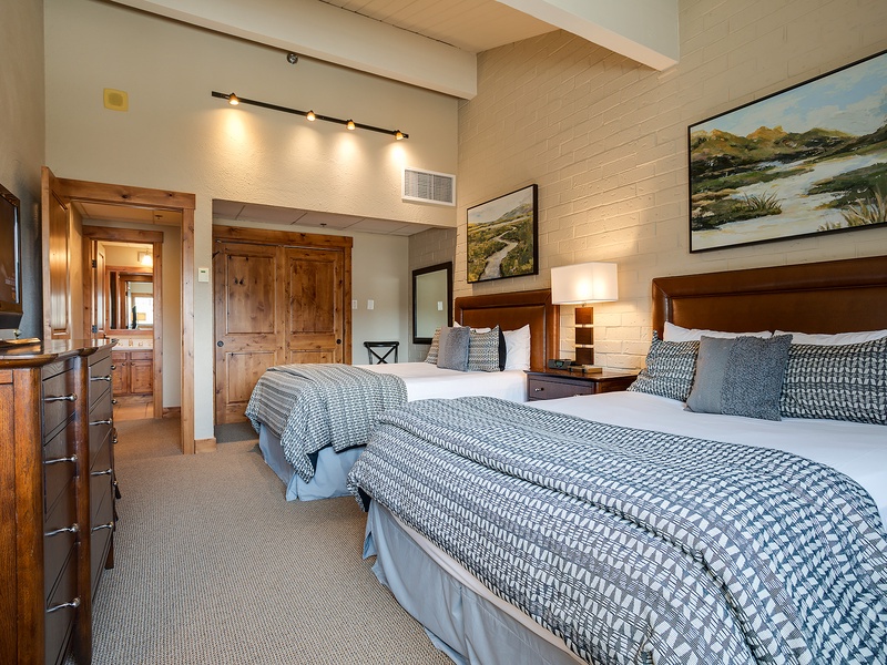 Sink into plush bedding and feel right at home in this bright, welcoming guest room featuring twin beds, elegant furnishings, charming artwork, and high ceilings that invite complete relaxation and restful sleep.