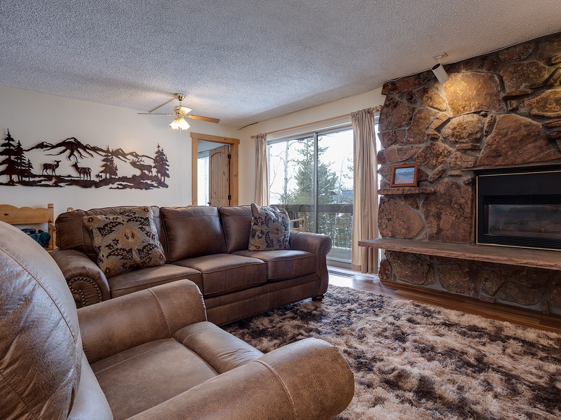 Settle into plush leather sofas beside a stunning stone fireplace, where rustic mountain charm meets modern comfort. Large windows frame scenic views while you relax in this cozy, inviting living room.
