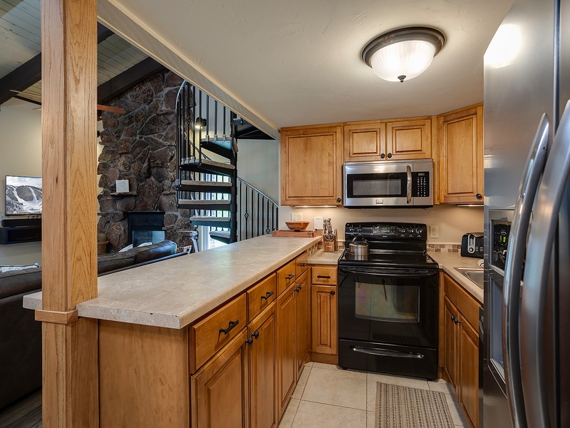 Your fully equipped kitchen features modern appliances, ample counter space, and warm wood cabinetry—perfect for preparing meals after a day of mountain adventures.