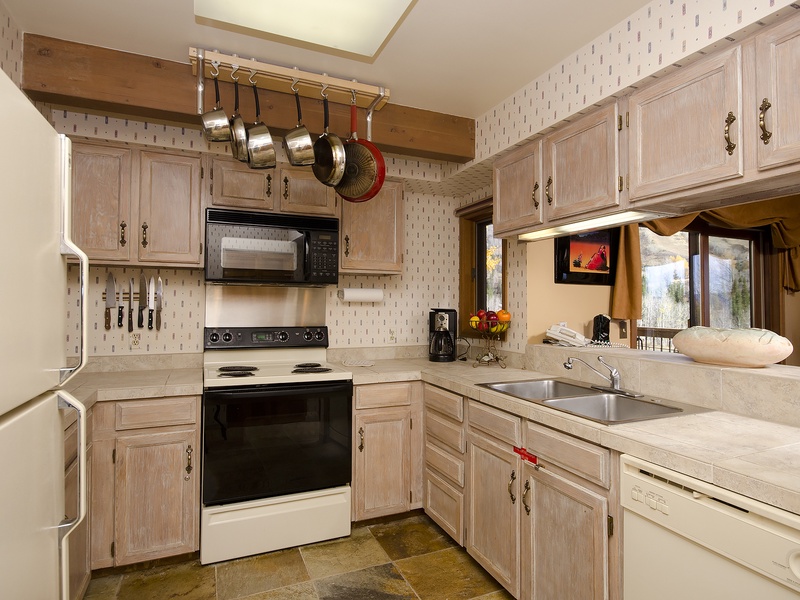 You'll love preparing meals in this fully equipped kitchen, where pots and pans hang within easy reach, bright counters offer plenty of space, and natural light pours in through the window.
