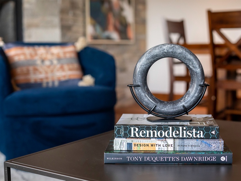 Sink into plush seating with a curated stack of design books at your fingertips, where stylish decor and cozy textures invite you to relax and unwind.